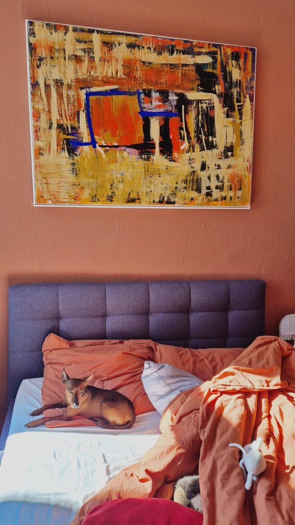 „Glut“: Orange, Schwarz und Blau, über einem Bett hängend