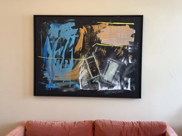 „X9Blue“ gerahmt über einem rosafarbenen Sofa